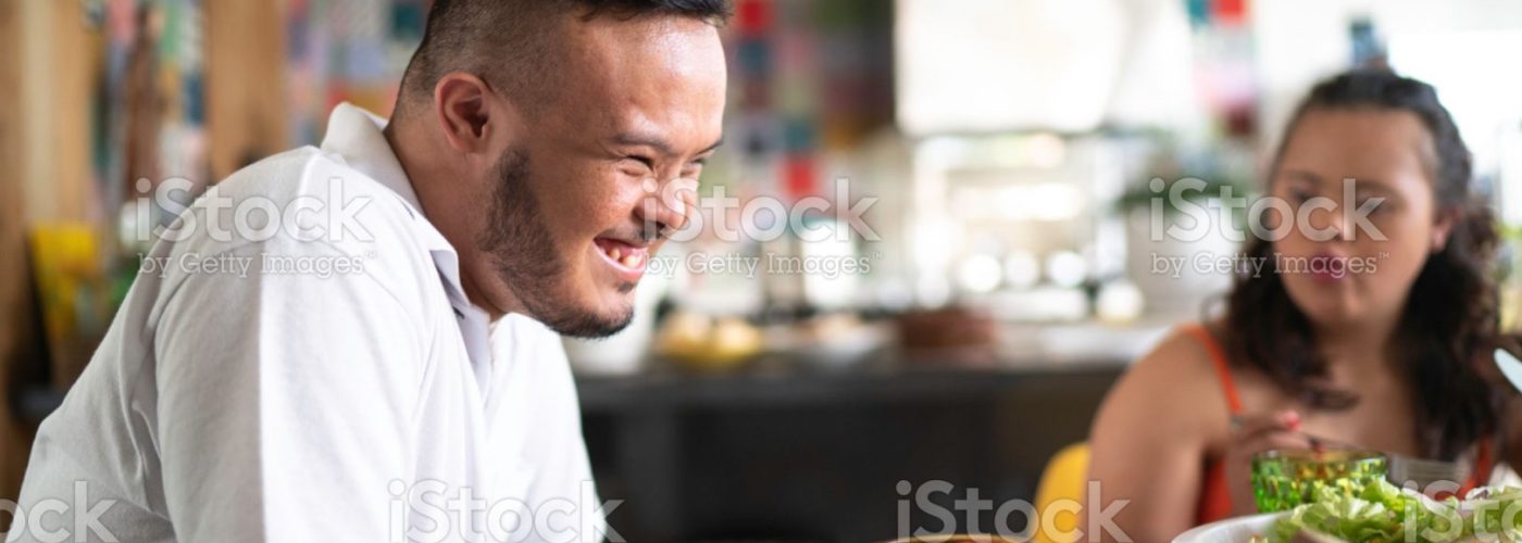Profile view of special needs boy laughing at lunch time